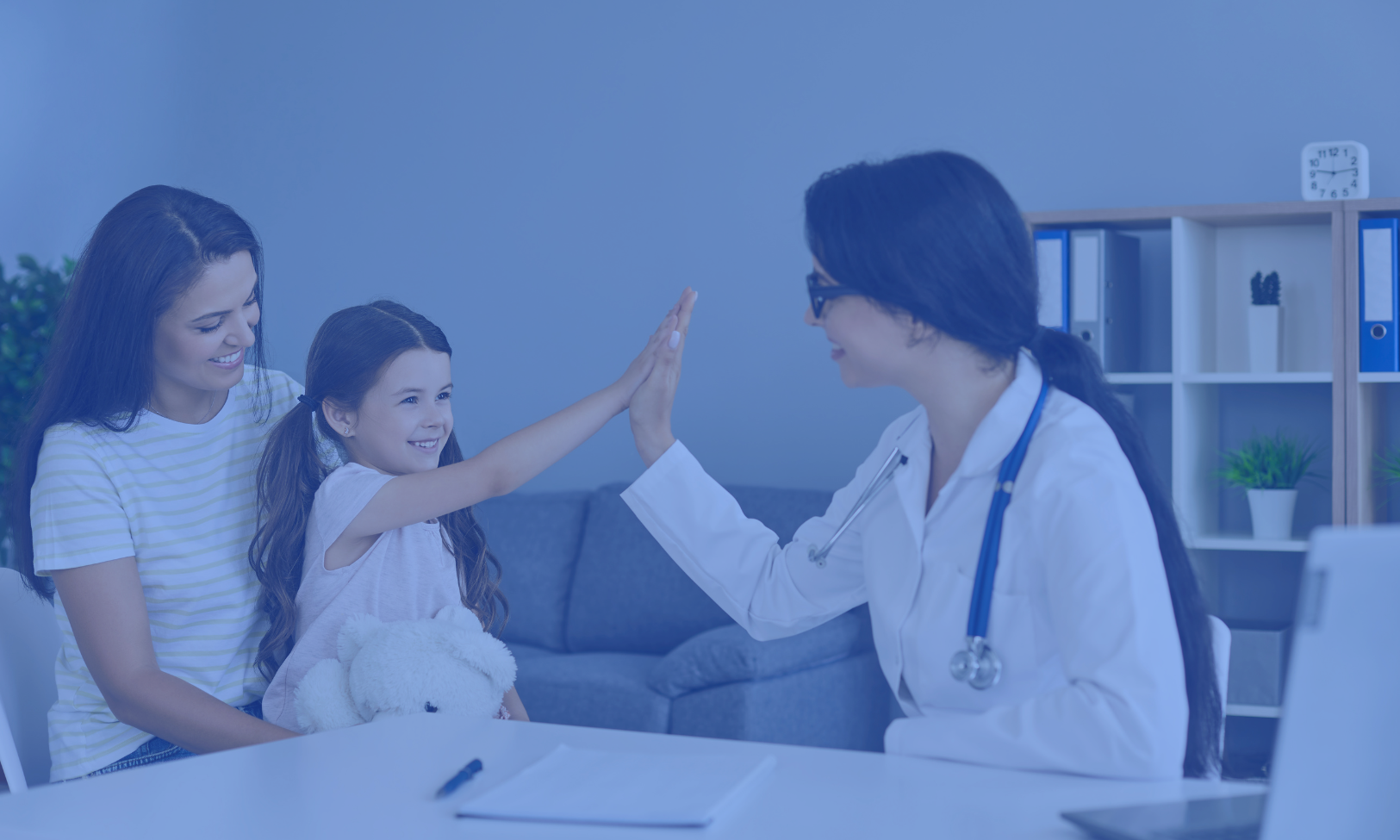 Image of a young girl with brown hair high-fiving her female doctor during a medical appointment, with her mother watching and smiling. The setting is a modern doctor's office, illustrating a supportive and positive healthcare environment for children. The doctor is dressed in a white lab coat, suggesting a professional and caring interaction.