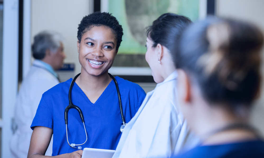 Image of a young girl with brown hair high-fiving her female doctor during a medical appointment, with her mother watching and smiling. The setting is a modern doctor's office, illustrating a supportive and positive healthcare environment for children. The doctor is dressed in a white lab coat, suggesting a professional and caring interaction.
