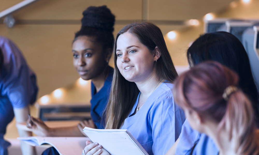 Image of a young girl receiving a medical examination from a nurse using a digital thermometer, while her mother closely watches. The nurse, in blue scrubs, is attentively engaging with the child, who appears calm. The mother, standing beside her daughter, looks on with concern. The setting is a medical office, illuminated in a serene blue tone to create a calm and professional atmosphere.