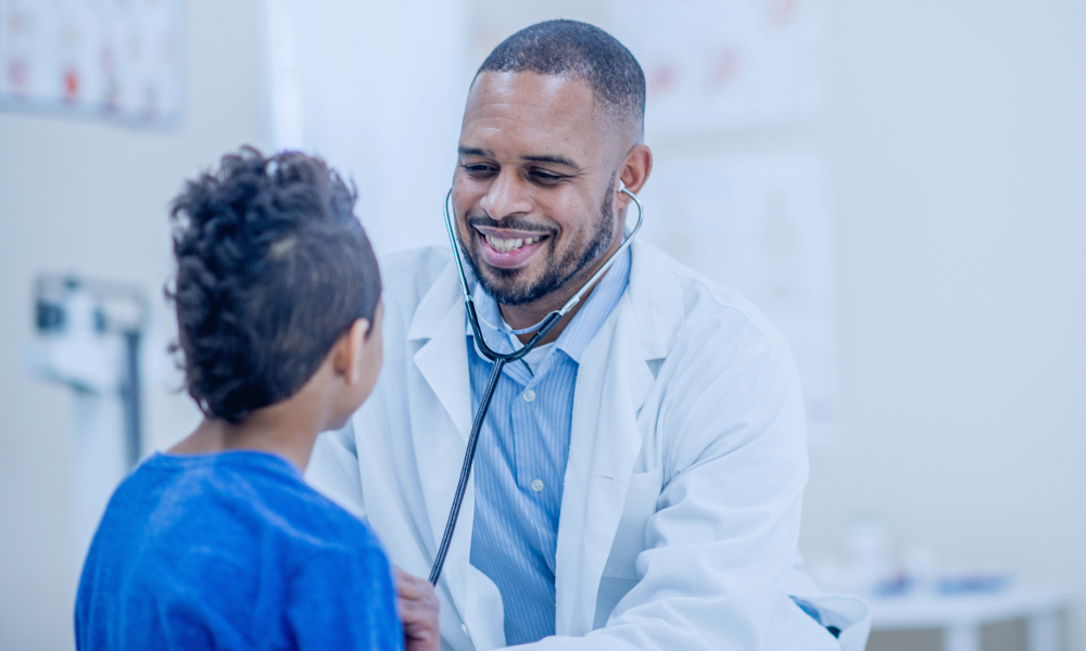 Image of a young girl receiving a medical examination from a nurse using a digital thermometer, while her mother closely watches. The nurse, in blue scrubs, is attentively engaging with the child, who appears calm. The mother, standing beside her daughter, looks on with concern. The setting is a medical office, illuminated in a serene blue tone to create a calm and professional atmosphere.